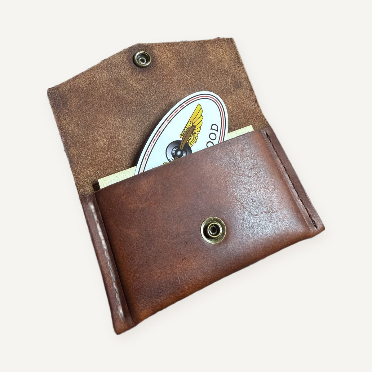 Open leather card pouch holding pilot trading cards and a Wings & Wood sticker